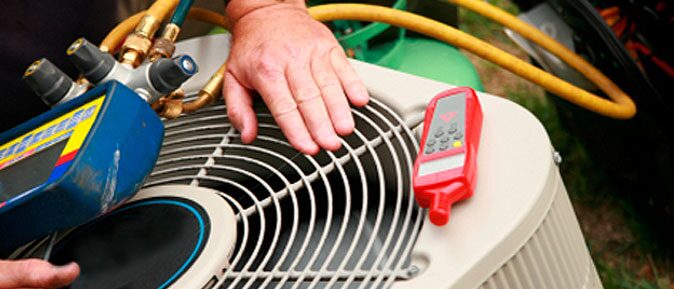 Service technician taking readings at the coil of a condensing unit